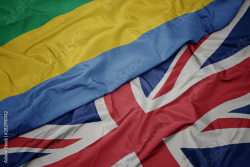 waving colorful flag of great britain and national flag of gabon.