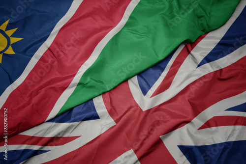 waving colorful flag of great britain and national flag of namibia.