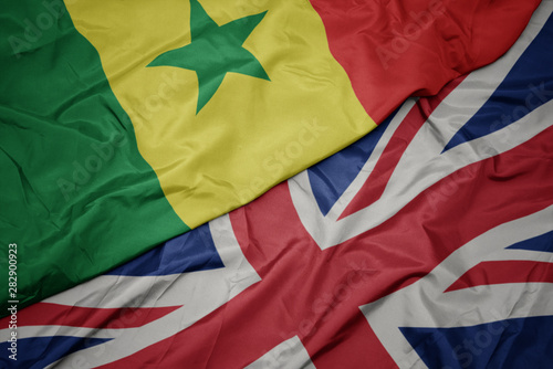 waving colorful flag of great britain and national flag of senegal.