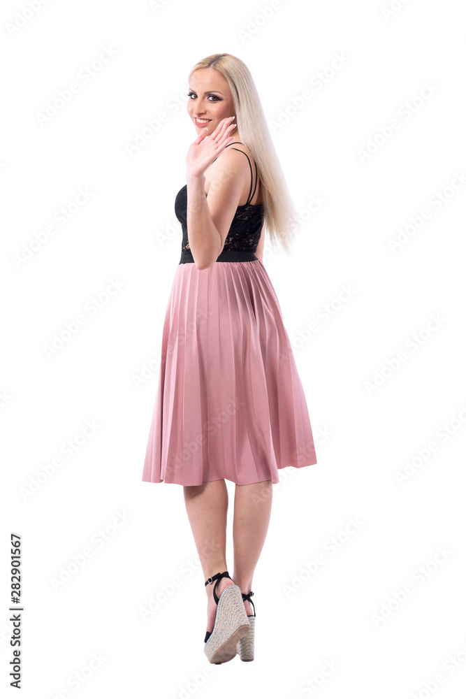Back view of young blonde stylish woman in skirt walking away turning and waving hand goodbye to camera. Full body isolated on white background. Back view of young blonde stylish woman in skirt walking away turning and waving hand goodbye to camera. Full body isolated on white background.