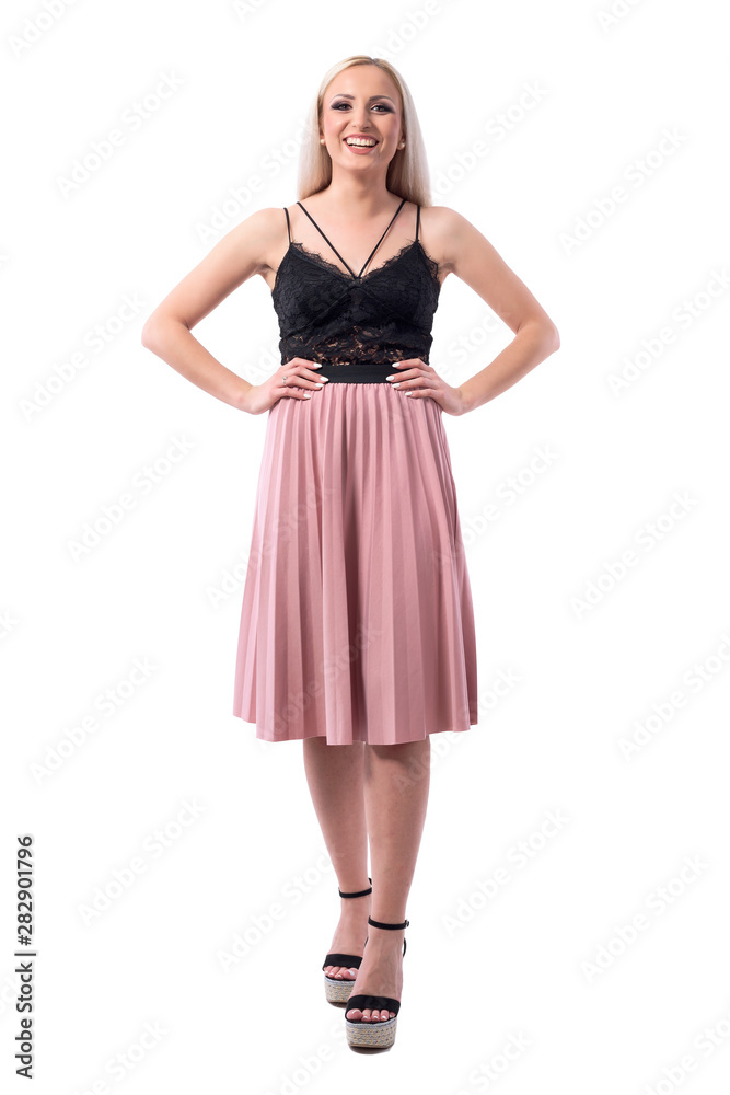 Candid laughing young beautiful blonde woman in pleated salmon skirt looking at camera. Full body isolated on white background. 