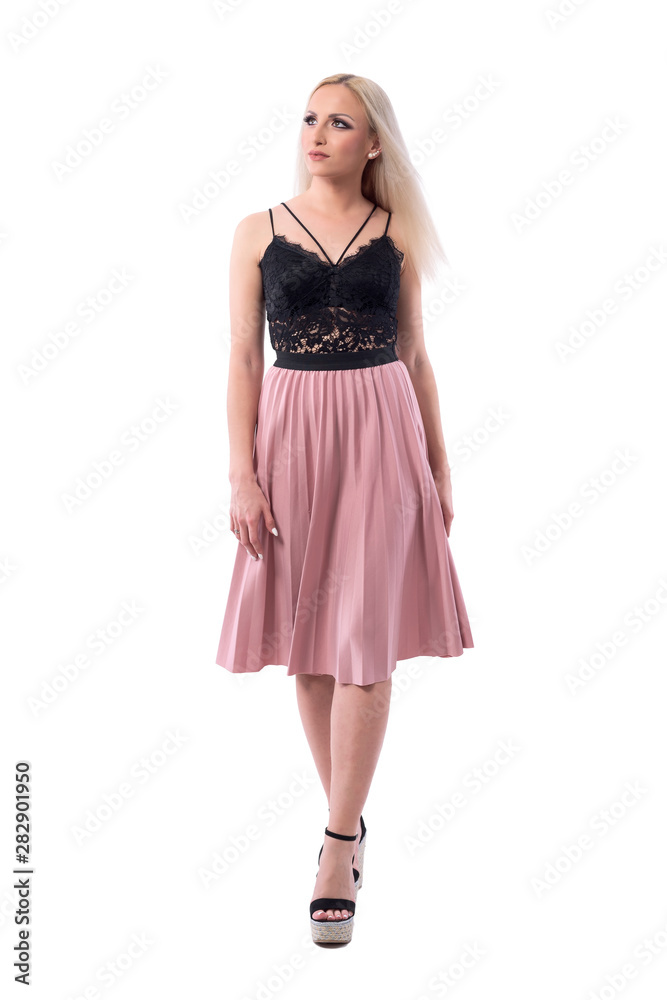 Confident comfortable happy young blonde hair woman in lace top and salmon skirt walking and looking up. Full body isolated on white background. Confident comfortable happy young blonde hair woman in lace top and salmon skirt walking and looking up. Full body isolated on white background.