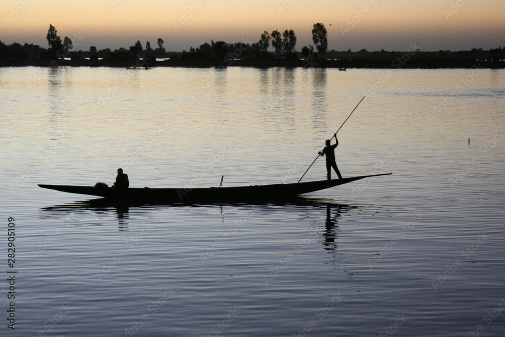 A boat and its crew are silhouetted against the River Bani at dusk in Mopti, Mali on 8 December 2007