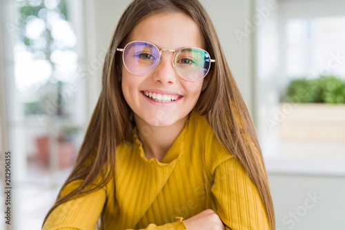 Beautiful young girl kid wearing glasses smiling looking side and staring away thinking. photo
