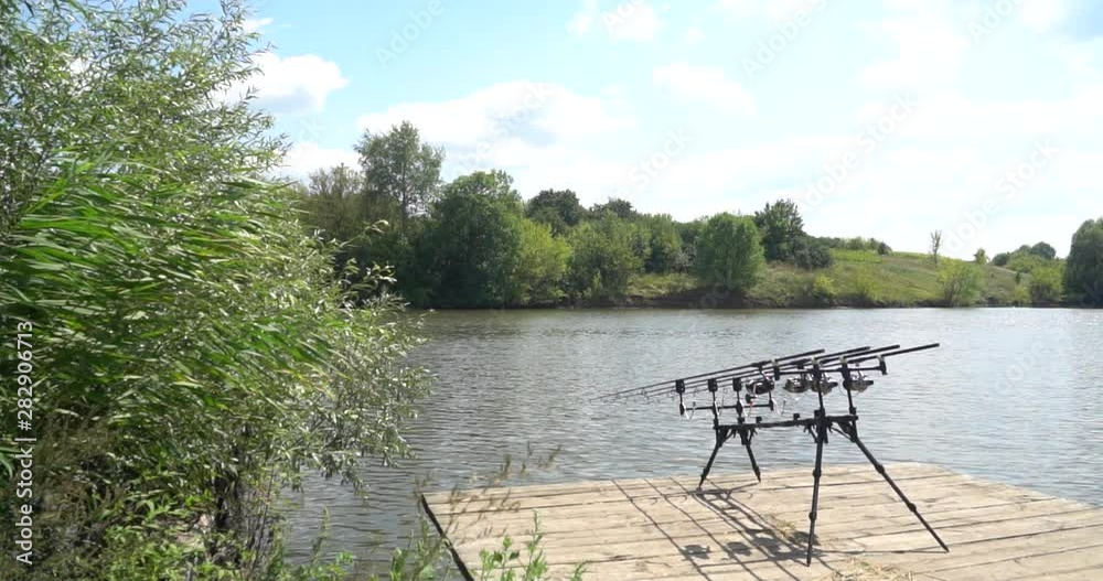 Slow motion, carp fishing, rod under, fishing rods, reels on a wooden platform Slow motion, carp fishing, rod under, fishing rods, reels on a wooden platform