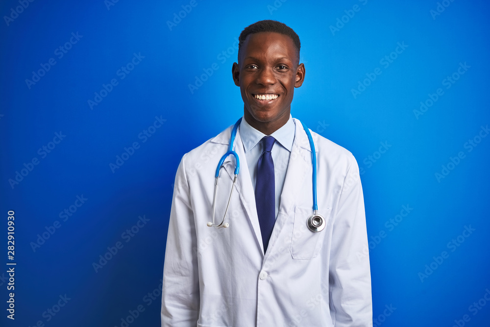African american doctor man wearing stethoscope standing over isolated blue background with a happy and cool smile on face. Lucky person. African american doctor man wearing stethoscope standing over isolated blue background with a happy and cool smile on face. Lucky person.