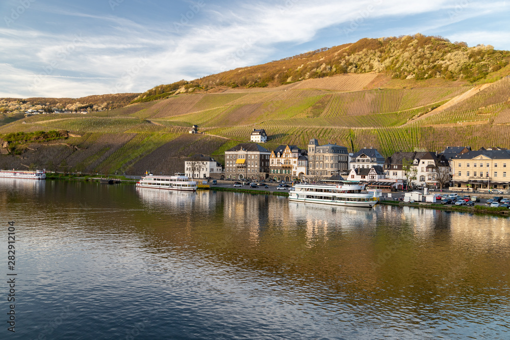 Obraz premium View at the city of Bernkastel-Kues at river Moselle with passenger ships and mountains with vineyards in the background