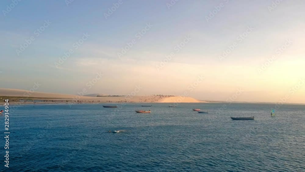 Aerial: Boats on Beautiful Blue Water in front of Sand Dunes, Ilha do Guajiru, Brazil