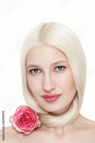 Portrait of young beautiful blonde woman with clean makeup and pink rose