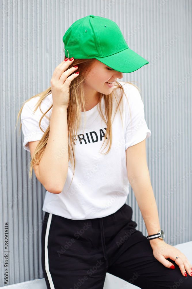 Beautiful blonde girl in a green cap on a background of a gray wall Beautiful blonde girl in a green cap on a background of a gray wall