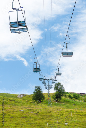 Chair lift, cable car in Switzerland during summer, with green grass en blue sky