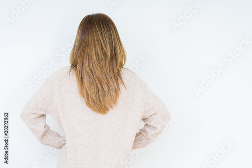 Beautiful middle age woman over isolated background standing backwards looking away with arms on body