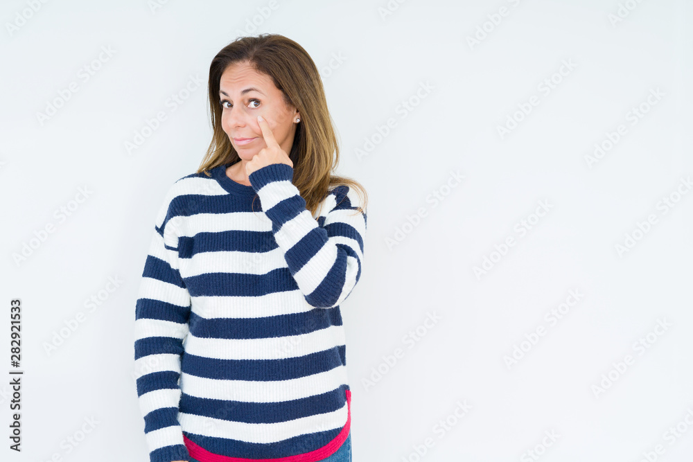 Beautiful middle age woman wearing navy sweater over isolated background Pointing to the eye watching you gesture, suspicious expression Beautiful middle age woman wearing navy sweater over isolated background Pointing to the eye watching you gesture, suspicious expression