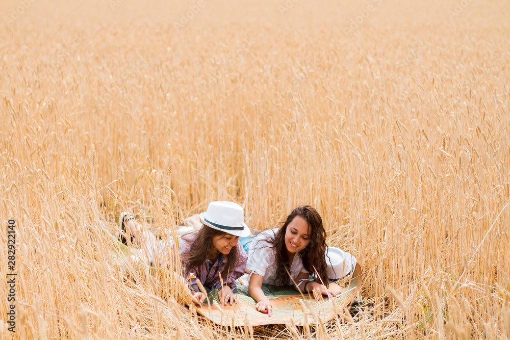 Two girls are lying in a field with a map in summer laughing. Two girls are lying in a field with a map in summer laughing.