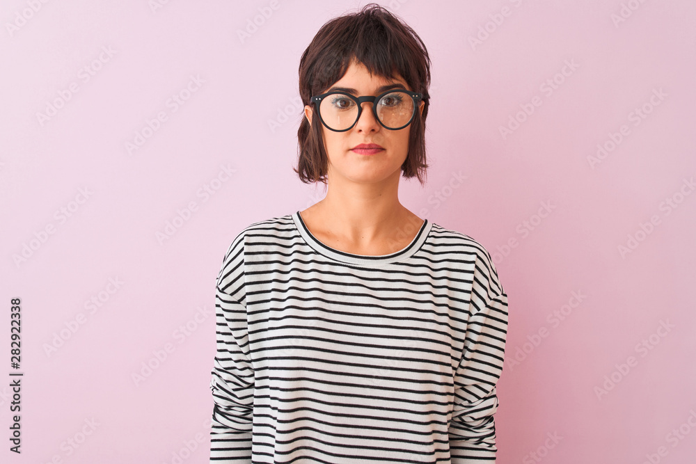 Young beautiful woman wearing striped t-shirt and glasses over isolated pink background Relaxed with serious expression on face. Simple and natural looking at the camera. Young beautiful woman wearing striped t-shirt and glasses over isolated pink background Relaxed with serious expression on face. Simple and natural looking at the camera.