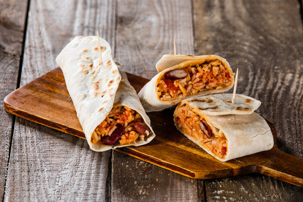 Burritos on cutting board on wooden table