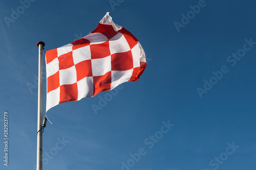 Red and white checkered flag of North Brabant the southern part of the Netherlands waving on a blue sky photo