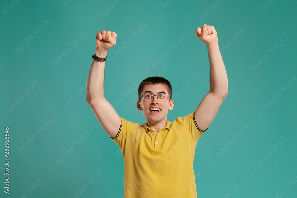 Handsome guy in a yellow casual t-shirt is posing over a blue background. Handsome guy in a yellow casual t-shirt is posing over a blue background.