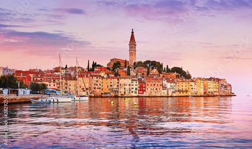 Rovinj Croatia. Sunrise sky above vintage town at Istria peninsula in Adriatic Sea. View from water at old Mediterranean architecture buildings. Coastline and tower of Church of Saint Euphemia. photo
