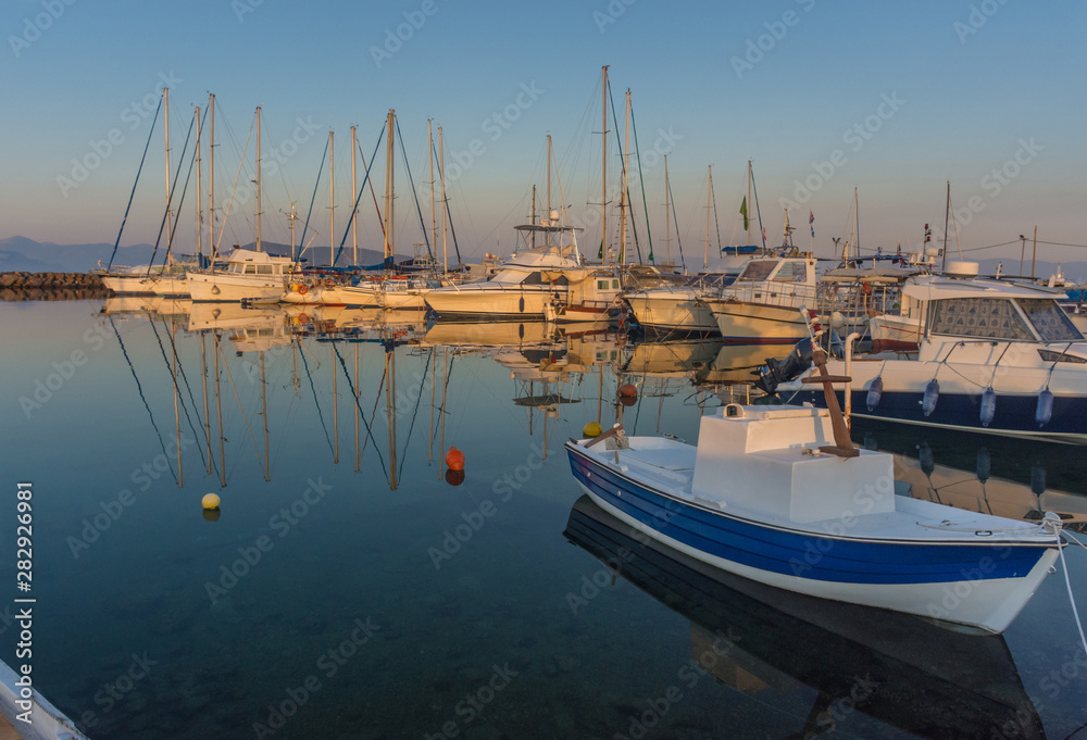 Port of Aegina town with yachts and fishermen boats docked in Aegina island, Saronic gulf, Greece, at sunrise.