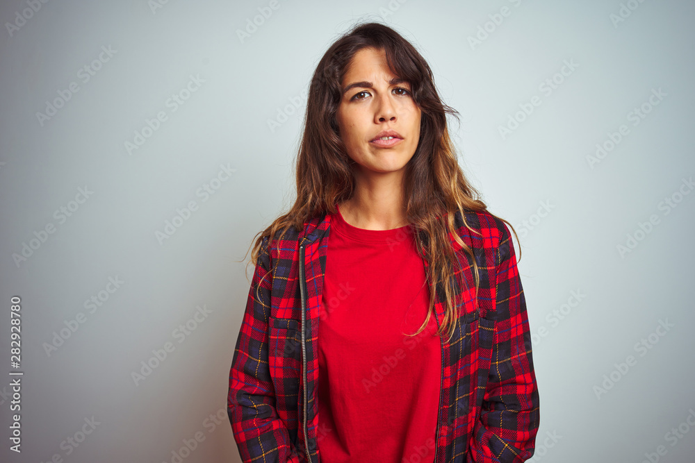 Young beautiful woman wearing red t-shirt and jacket standing over white isolated background skeptic and nervous, frowning upset because of problem. Negative person. Young beautiful woman wearing red t-shirt and jacket standing over white isolated background skeptic and nervous, frowning upset because of problem. Negative person.
