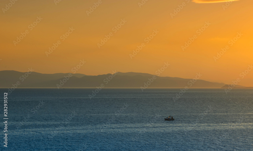 Fishermen boat at sunset in the Mediterranean Sea, near Aegina island, Saronic gulf, Greece.