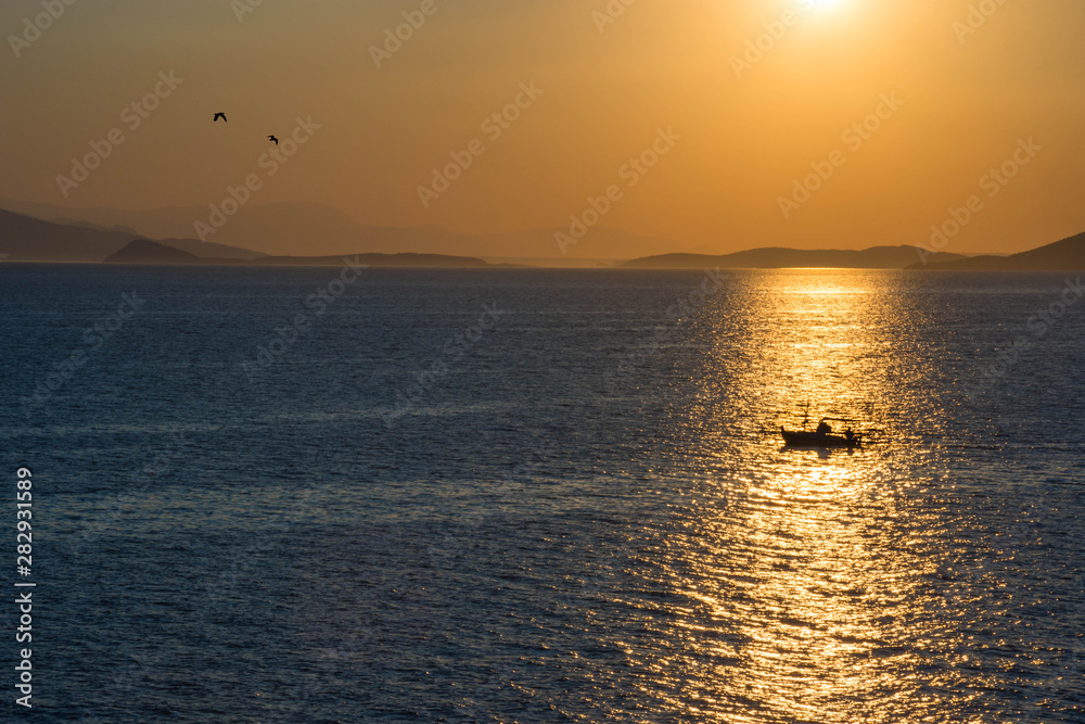 Fishermen boat at sunset in the Mediterranean Sea, near Aegina island, Saronic gulf, Greece.