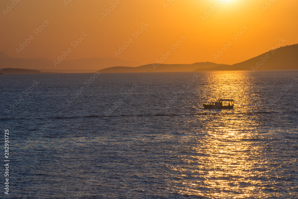 Fishermen boat at sunset in the Mediterranean Sea, near Aegina island, Saronic gulf, Greece.