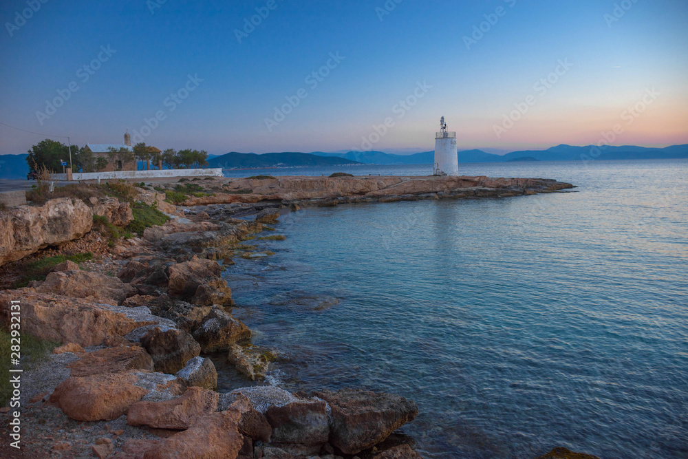 Fototapeta premium Old small lighthouse of the Aegina island, Saronic gulf, Greece, at sunset.