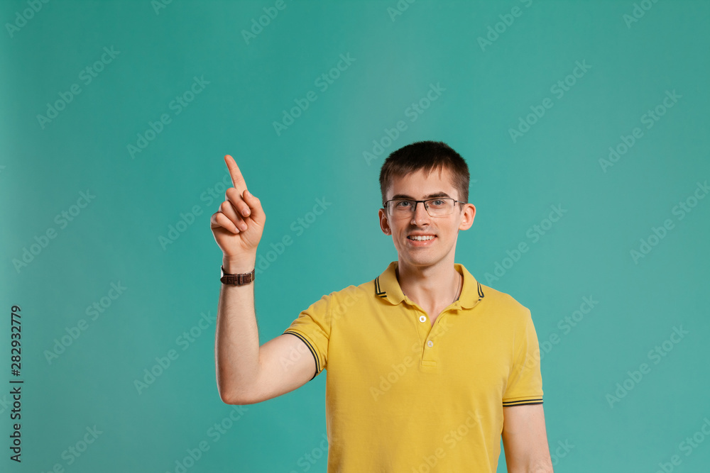 Handsome guy in a yellow casual t-shirt is posing over a blue background. Handsome guy in a yellow casual t-shirt is posing over a blue background.
