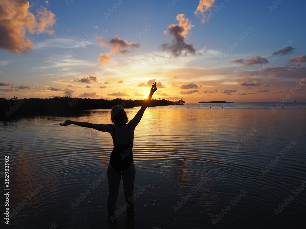 silhouette of woman in the sea  on sunset background of the sky