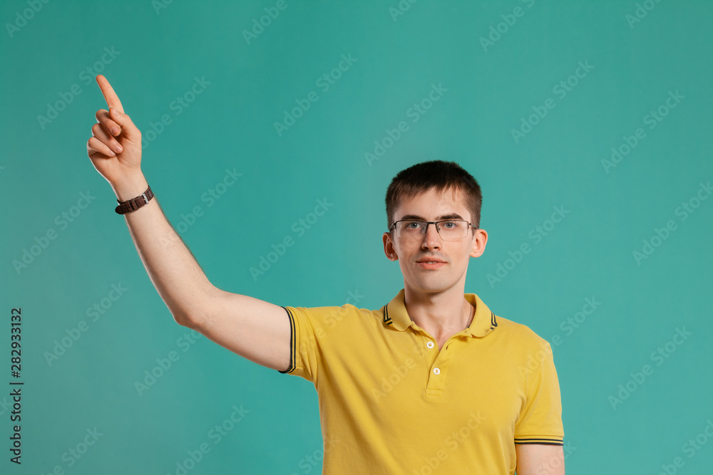 Handsome guy in a yellow casual t-shirt is posing over a blue background. Handsome guy in a yellow casual t-shirt is posing over a blue background.