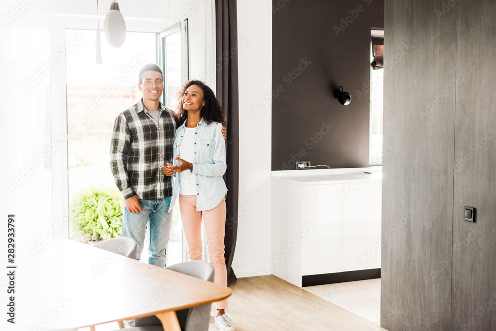 full length view of african american husband and wife hugging and looking at room full length view of african american husband and wife hugging and looking at room