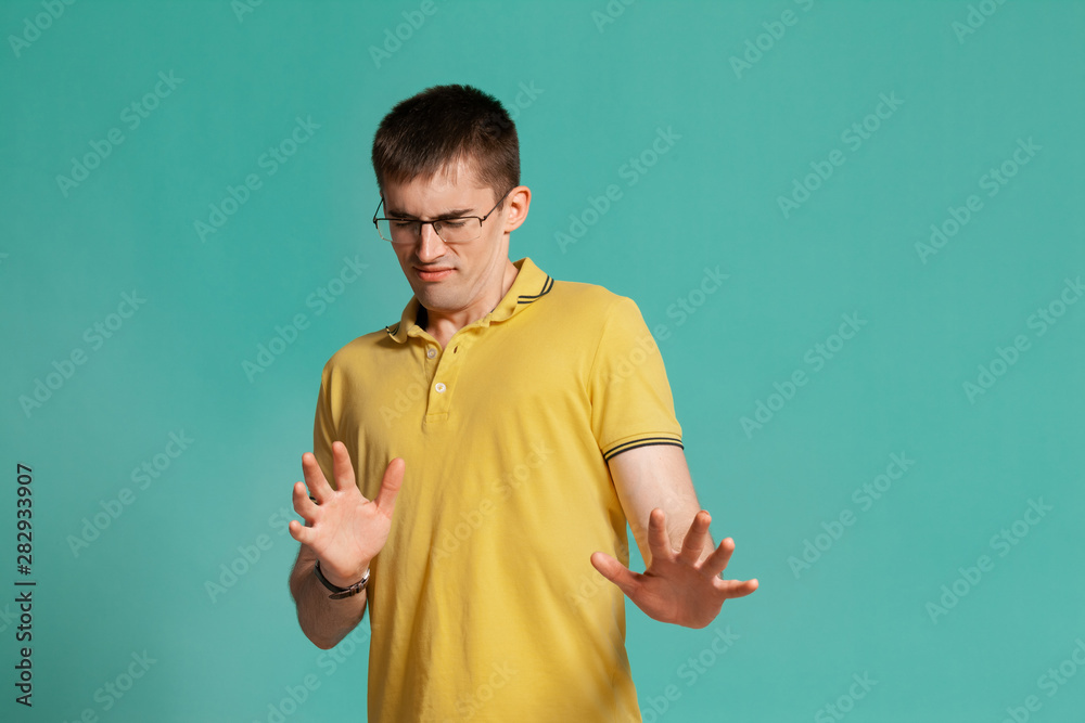 Handsome guy in a yellow casual t-shirt is posing over a blue background. Handsome guy in a yellow casual t-shirt is posing over a blue background.