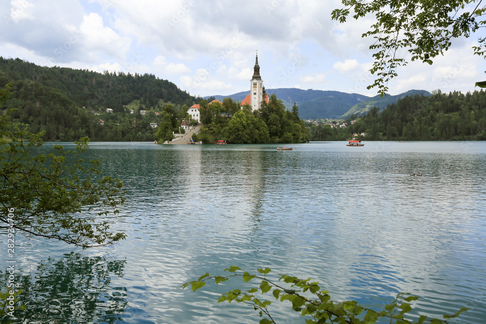 Obraz premium Lake Bled Slovenia. Beautiful mountain lake in summer with small Church on an island with castle on cliff and european alps in the background.