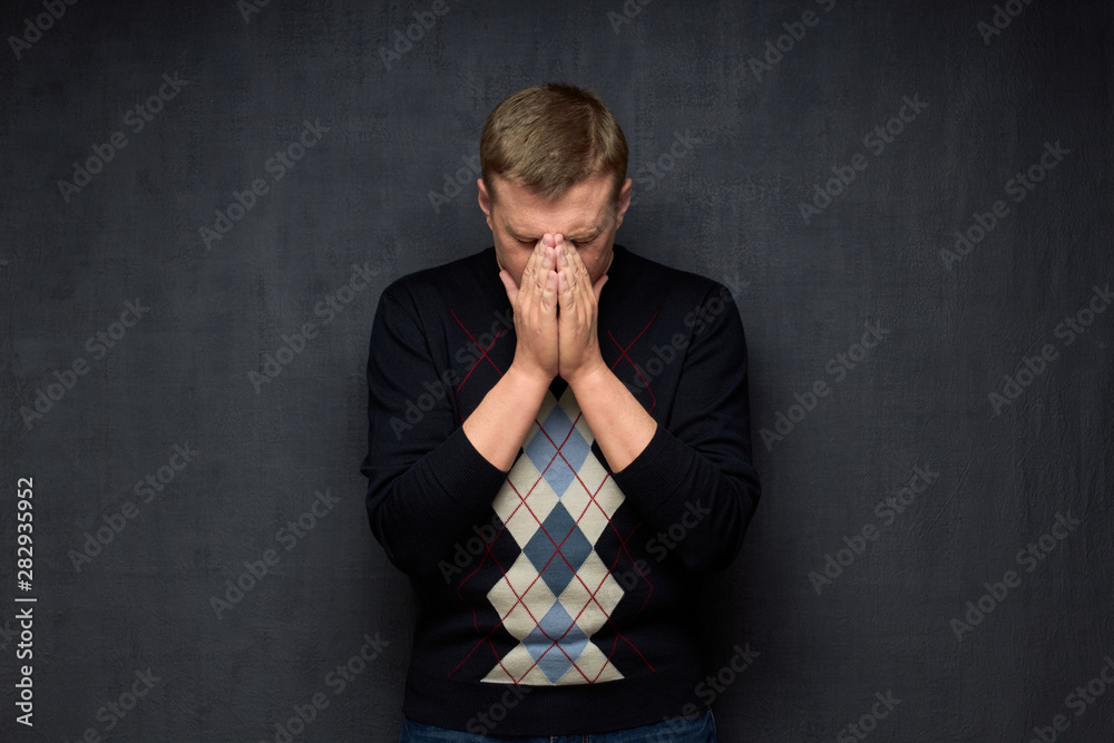 Portrait of unhappy man covering face with hands Portrait of unhappy man covering face with hands