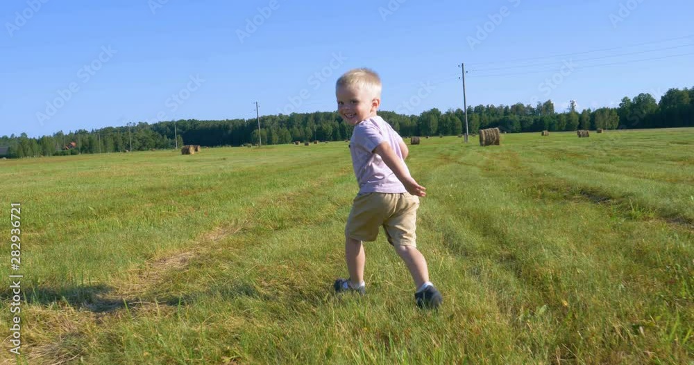 Cute little boy in shorts runs across the field and launches a toy airplane around a haystack and corn field. Concept of: Play, Summer, Field, Eco, Happy. Cute little boy in shorts runs across the field and launches a toy airplane around a haystack and corn field. Concept of: Play, Summer, Field, Eco, Happy.
