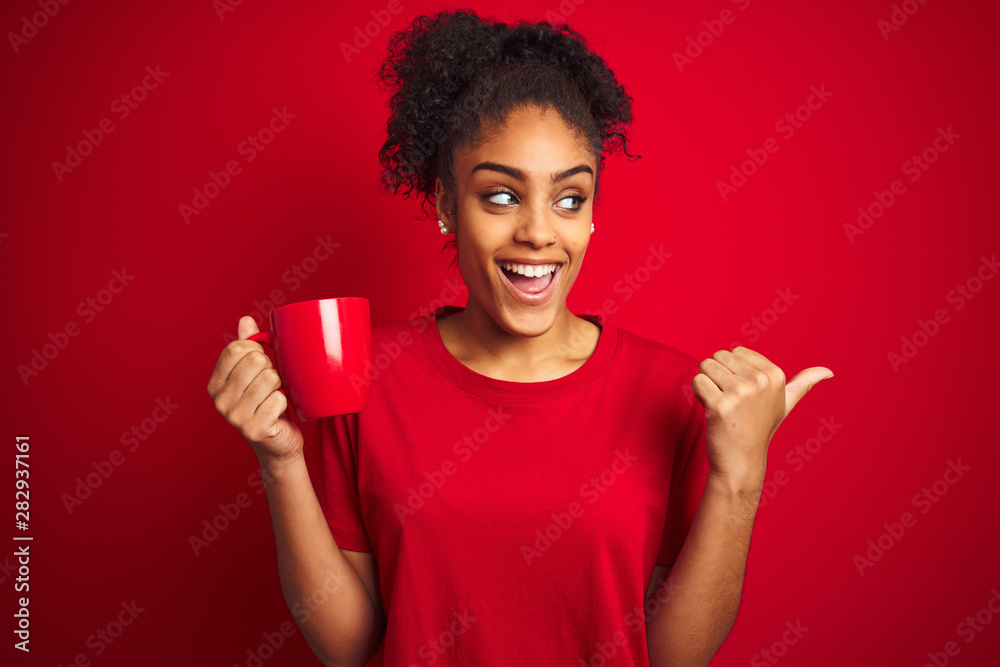 Young african american woman drinking a cup of coffee over isolated red background pointing and showing with thumb up to the side with happy face smiling Young african american woman drinking a cup of coffee over isolated red background pointing and showing with thumb up to the side with happy face smiling