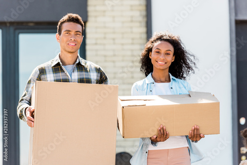 cople standing near house, looking at camera and holding boxes photo