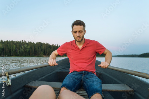 Man paddling in a boat towards the woods enjoying peaceful evening at the lake
