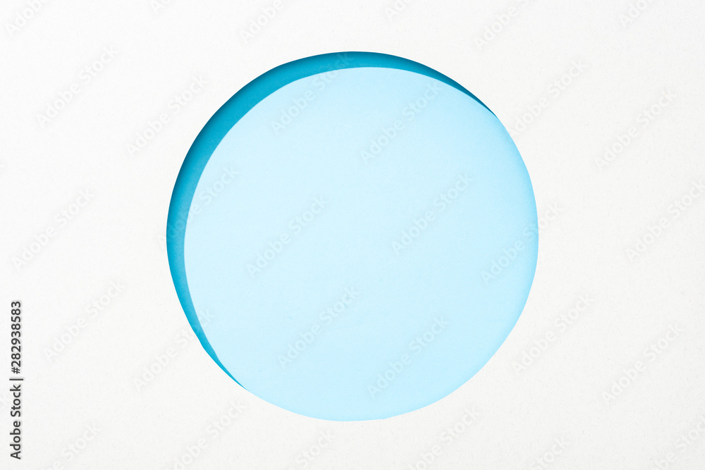 cut out round hole in white paper on light blue colorful background cut out round hole in white paper on light blue colorful background