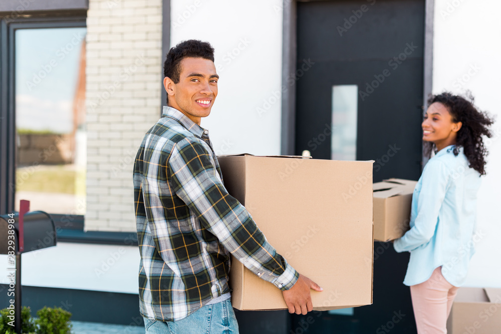 selective focus of african american man looking at camera while holding box selective focus of african american man looking at camera while holding box