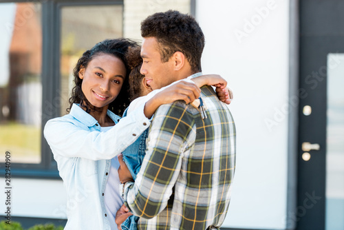 african american parents hugging while woman holding key and man holding daughter