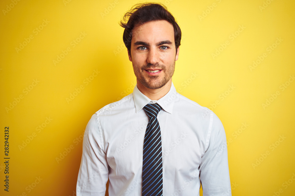 Young handsome businessman wearing elegant shirt and tie over isolated yellow background with a happy and cool smile on face. Lucky person. Young handsome businessman wearing elegant shirt and tie over isolated yellow background with a happy and cool smile on face. Lucky person.