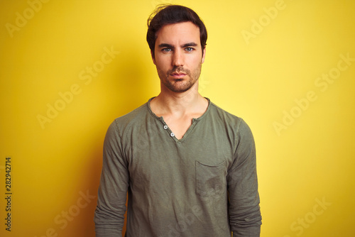 Wallpaper Mural Young handsome man wearing casual t-shirt standing over isolated yellow background Relaxed with serious expression on face. Simple and natural looking at the camera. Torontodigital.ca