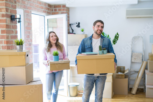 Young beautiful couple very happy together holding cardboard boxes moving to a new home