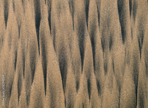 Graphic patterns in wet sand on beach in flat shadeless light, wet and hard surface. photo