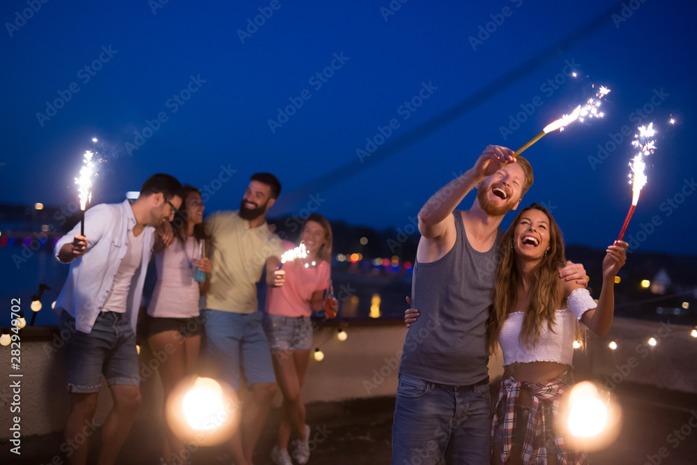 Friends enjoying a rooftop party and dancing with sparklers Friends enjoying a rooftop party and dancing with sparklers