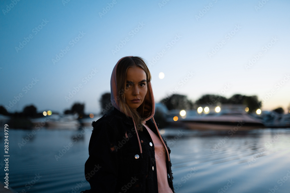 Blonde woman portrait standing by the river at night