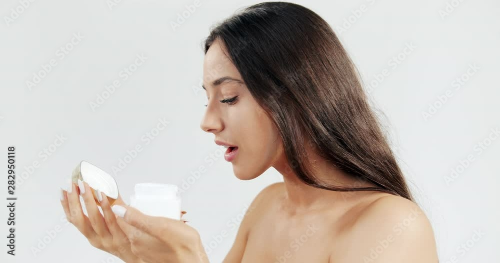 Attractive brunette female isolated on white background opening jar with cream and smelling it, natural cosmetics Attractive brunette female isolated on white background opening jar with cream and smelling it, natural cosmetics